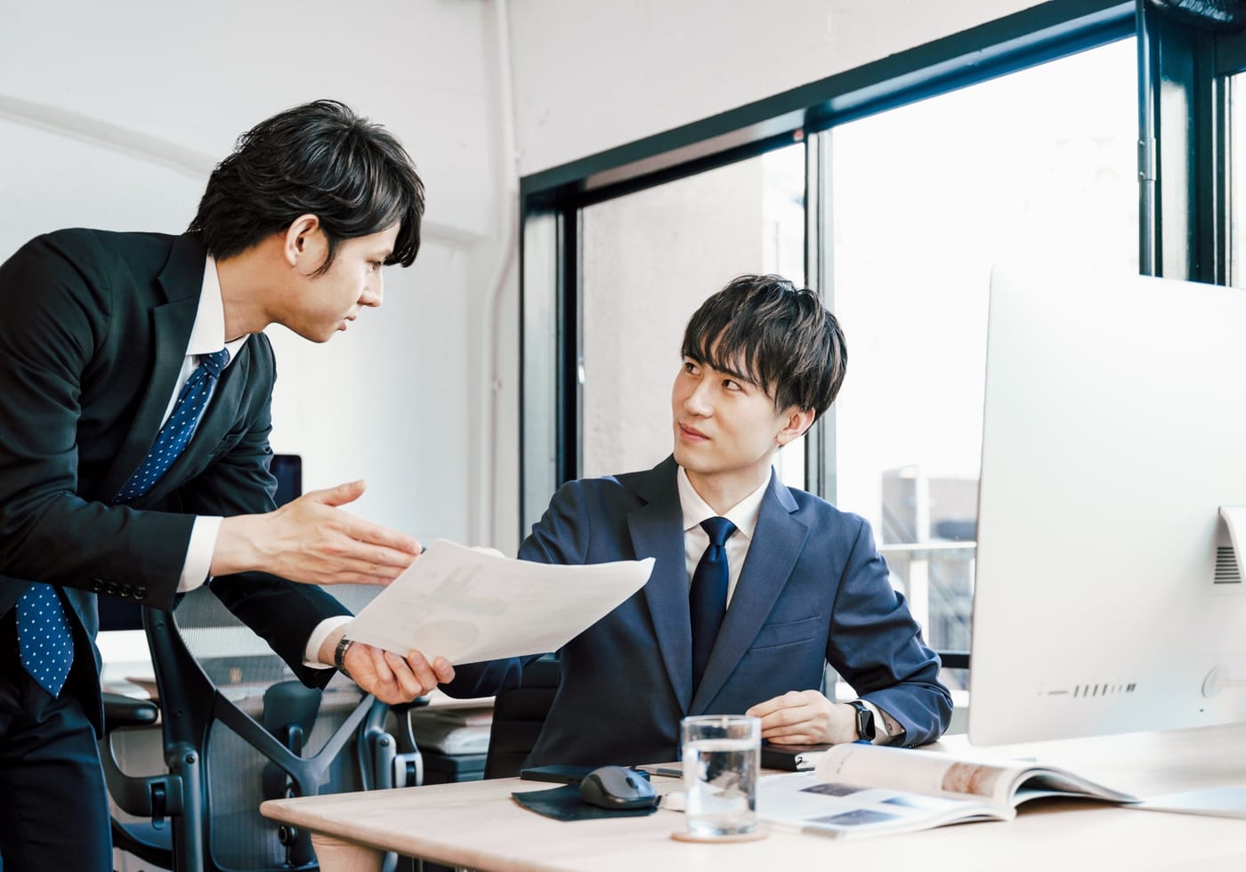 オフィスの打ち合わせで資料を見ながら話す二人